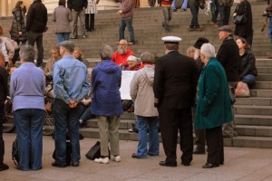 People standing facing into the circle, with passersby around them. 