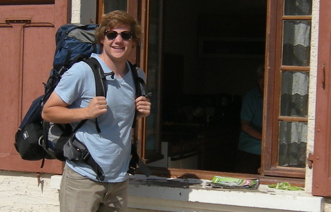 Drew standing with his backpack on next to an open window