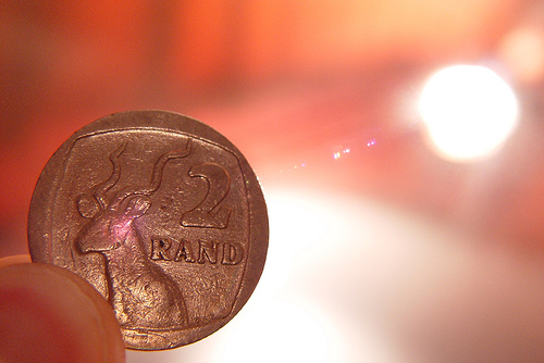A 2 Rand coin in the foreground with sunlight in the background
